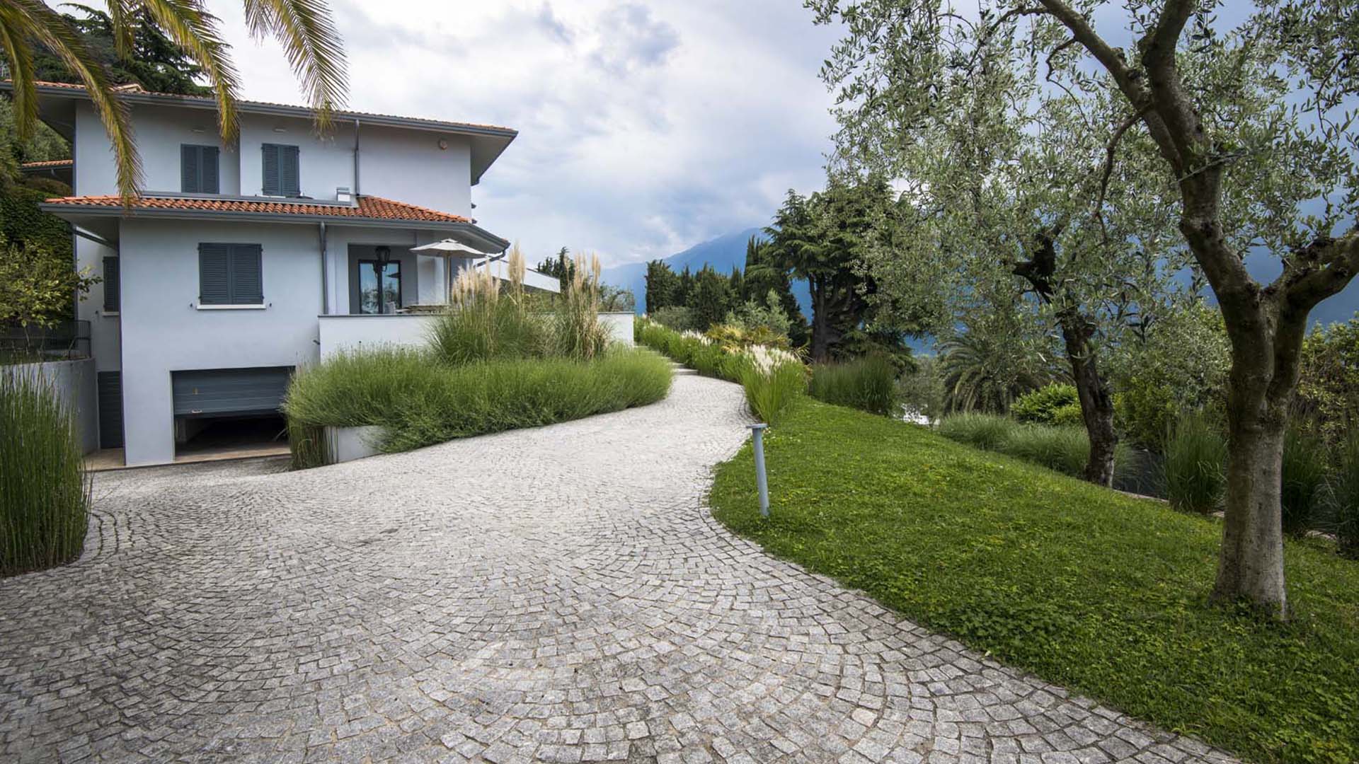 Giardino contemporaneo con graminacee, vialetto in pietra e impianto d’irrigazione invisibile