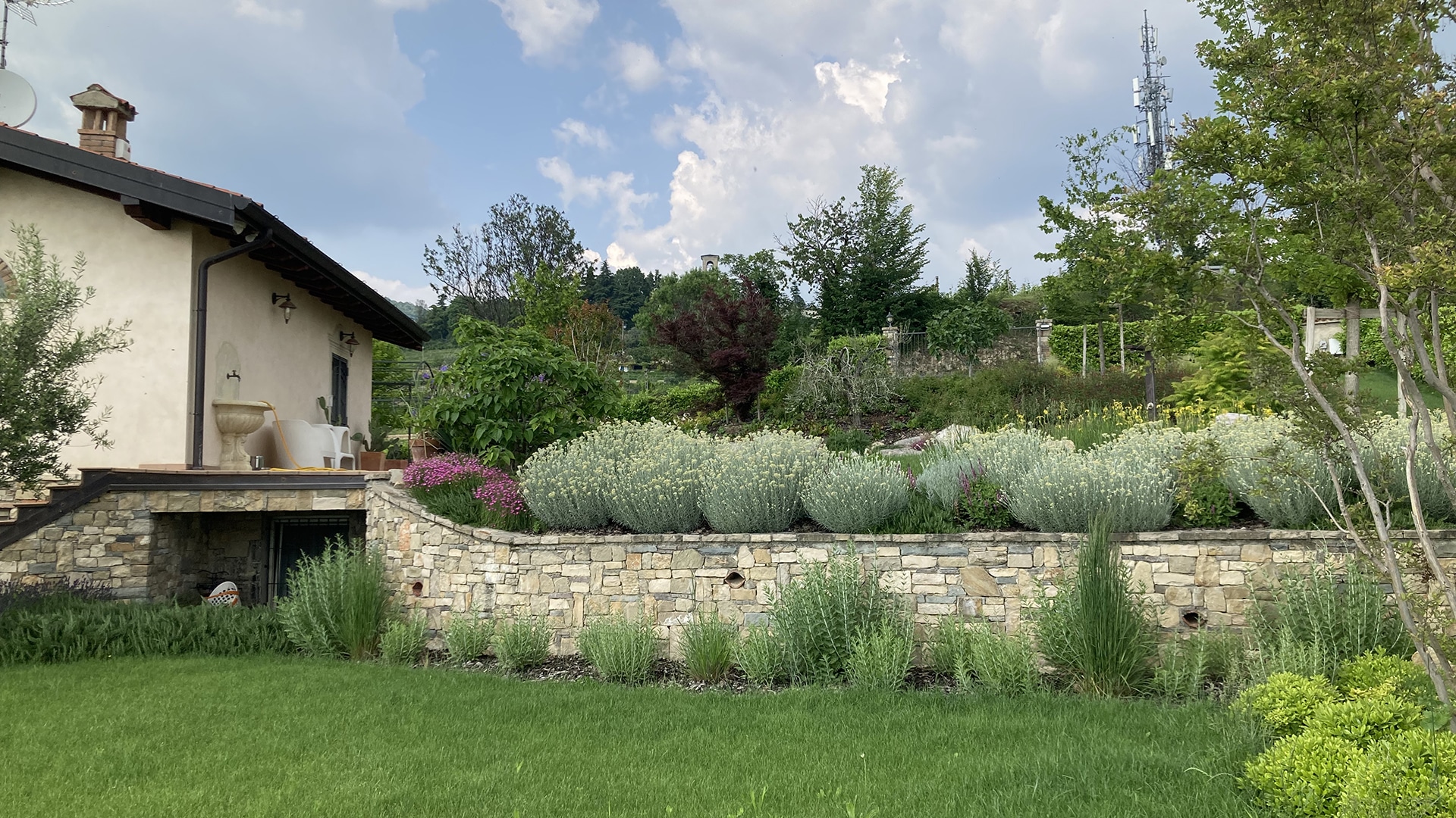 Scopri la parete fiorita e l'armonia delle piante disposte con cura da Grechi Giardini per un Natural Landscape Garden elegante e sostenibile.