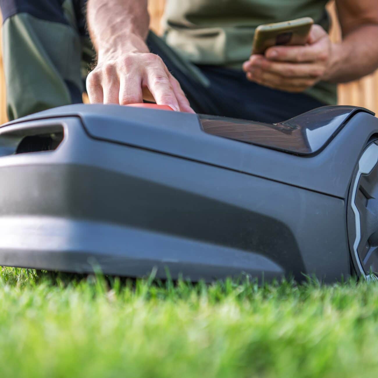 Grechi Giardini_Person Controlling a Robotic Lawn Mower Using a Smartphone on a Sunny Day in the Backyard