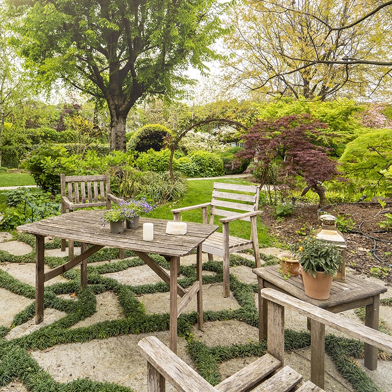 Area relax in giardino con arredi in legno e piante ornamentali