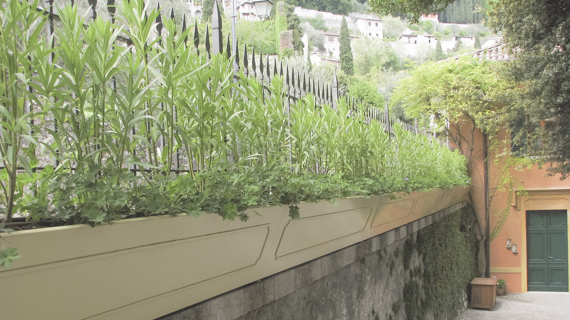 Fioriera fiorita su muretto perimetrale in giardino storico a Gargnano