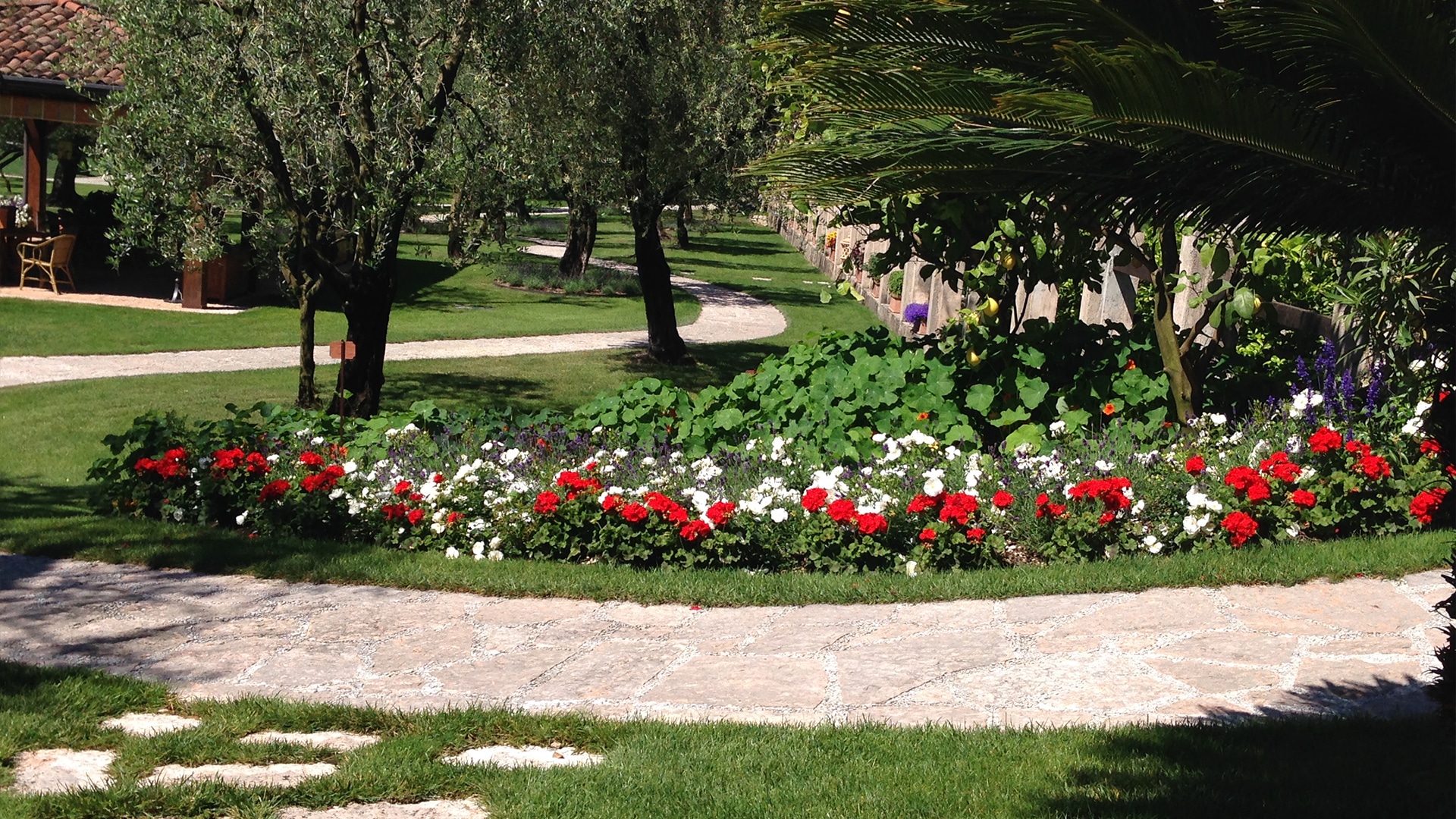 Giardino storico con roseto fiorito e struttura architettonica in pietra a Gargnano sul Lago di Garda