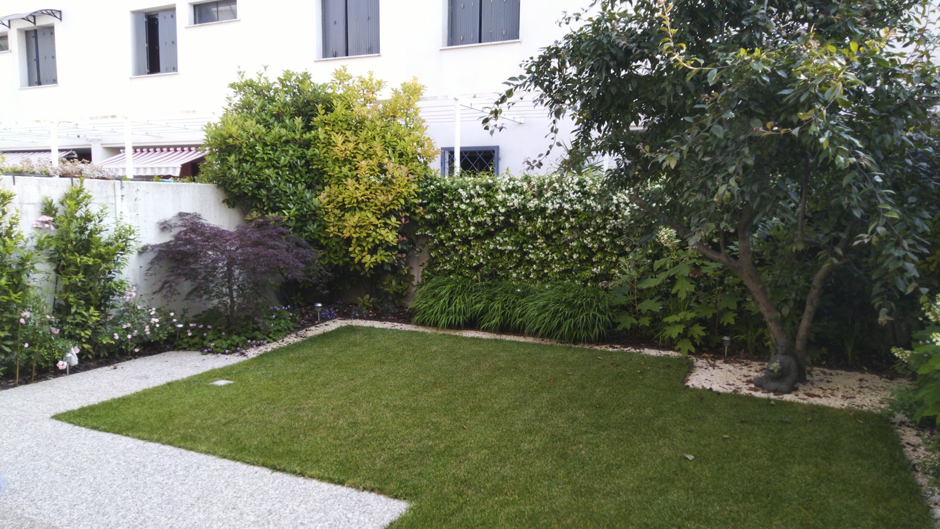 Giardino privato con prato verde all’inglese, siepi fiorite e piante ornamentali realizzato da Grechi Giardini.