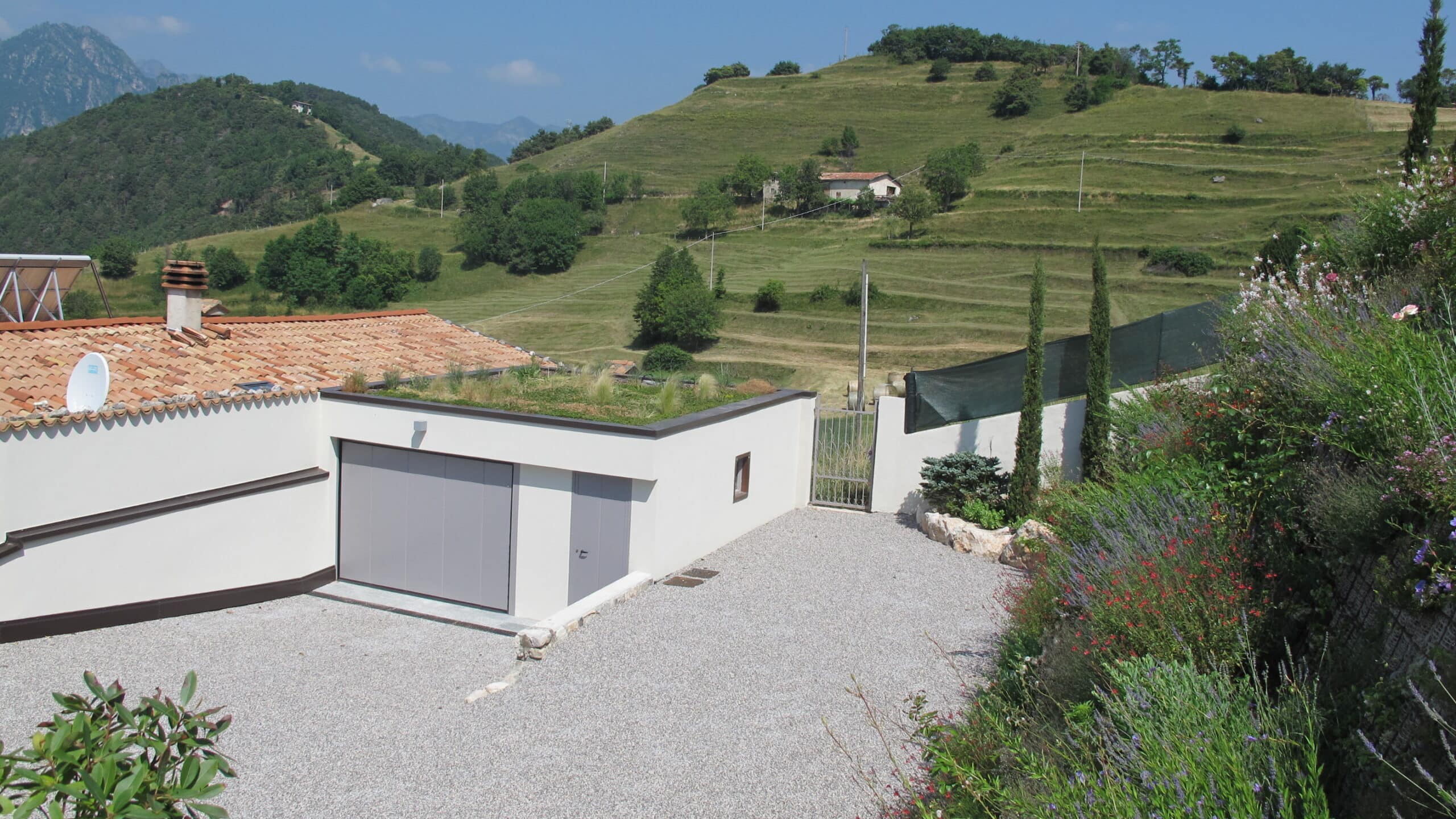 Giardino naturalistico ecosostenibile con tetto verde e bordure fiorite integrato nel paesaggio collinare, progettazione Grechi Giardini.